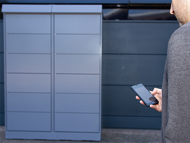 Over soulder view of customer approaching a locker with smart phone in hand