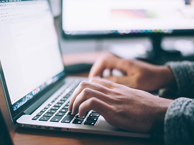 Hands typing on a laptop keyboard