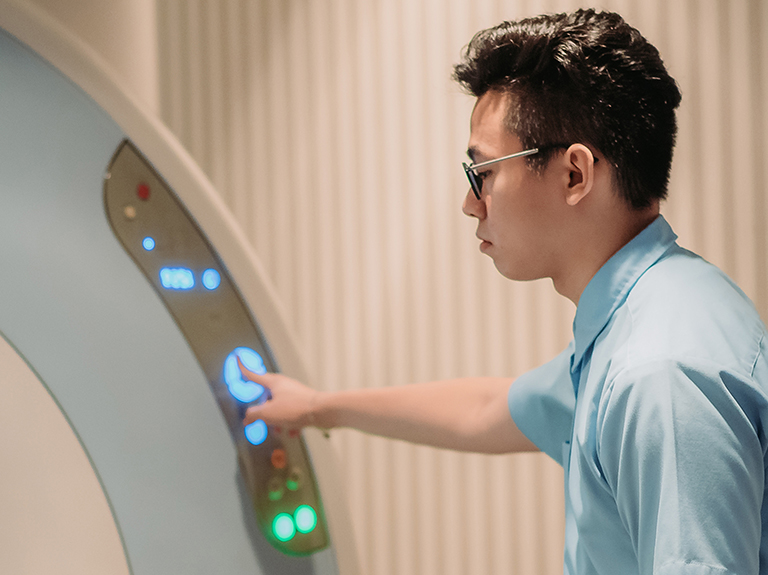 Asian chinese male nurse pressing a button on an MRI Scan at hospital