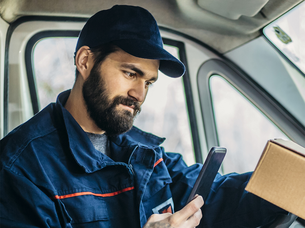 Delivery man scans a parcel with his phone.