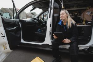 Female blue-collar worker sitting in her work van while on a job